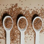 Flat lay of organic flaxseeds in wooden spoons showcasing natural nutrition and texture.